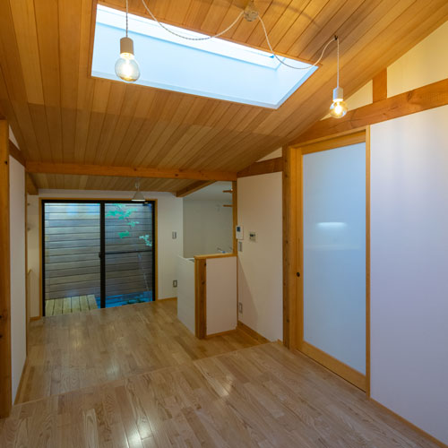 リビング
右の扉から洗面脱衣室・トイレ・浴室に入ります。
一段下がった奥はダイニング・キッチンです。