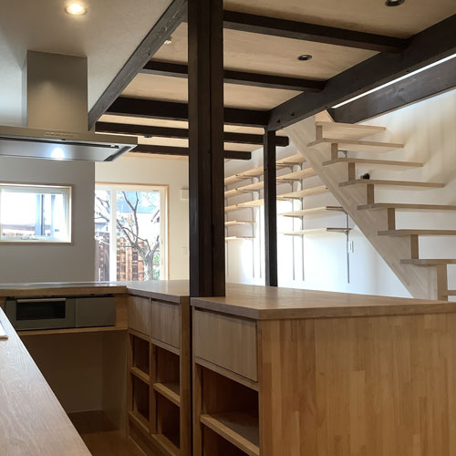 キッチン
平面で見ると「J」の形をしたカウンターキッチン
目線を考慮して、ダイニングより床の高さを下げている。
カウンターの向こうはリビングと2階へ上がる階段。